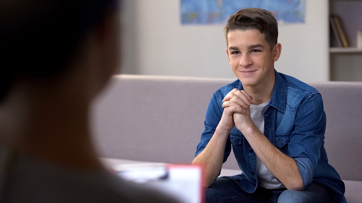 a child in a Medication Therapy Management program sits on a couch with their hands clasped