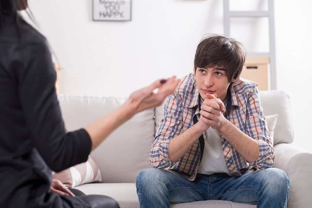 a young person sits on a couch talking to a counselor during benefits of individual therapy