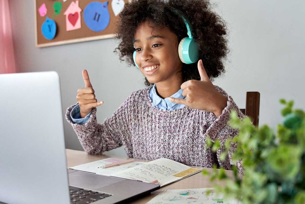 a young girl gives thumbs up to her computer during a teleheatlh mental health therapy session