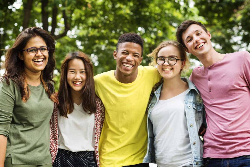 a group of teens embrace take a group photo in a therapy program for teen trauma