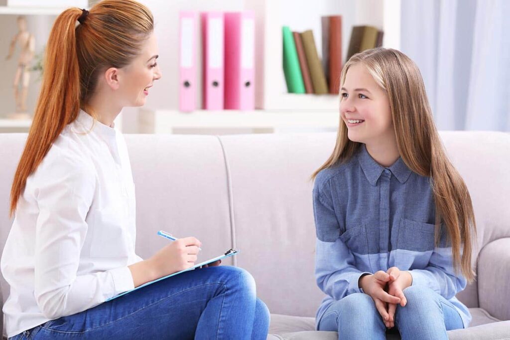 a person and a child sit on a couch and talk about Behavior Modification Therapy
