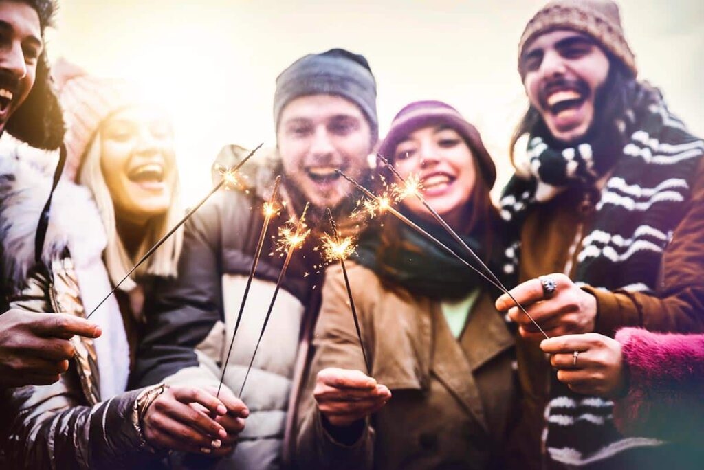 a group of teens celebrate the new year with sparklers after setting Mental Health Resolutions