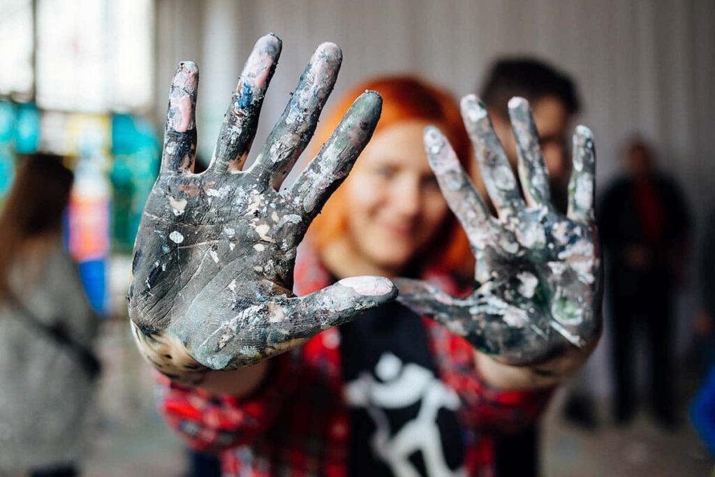 a teen holds up hands covered in paint after engaging in Therapeutic Activities for Mental Health