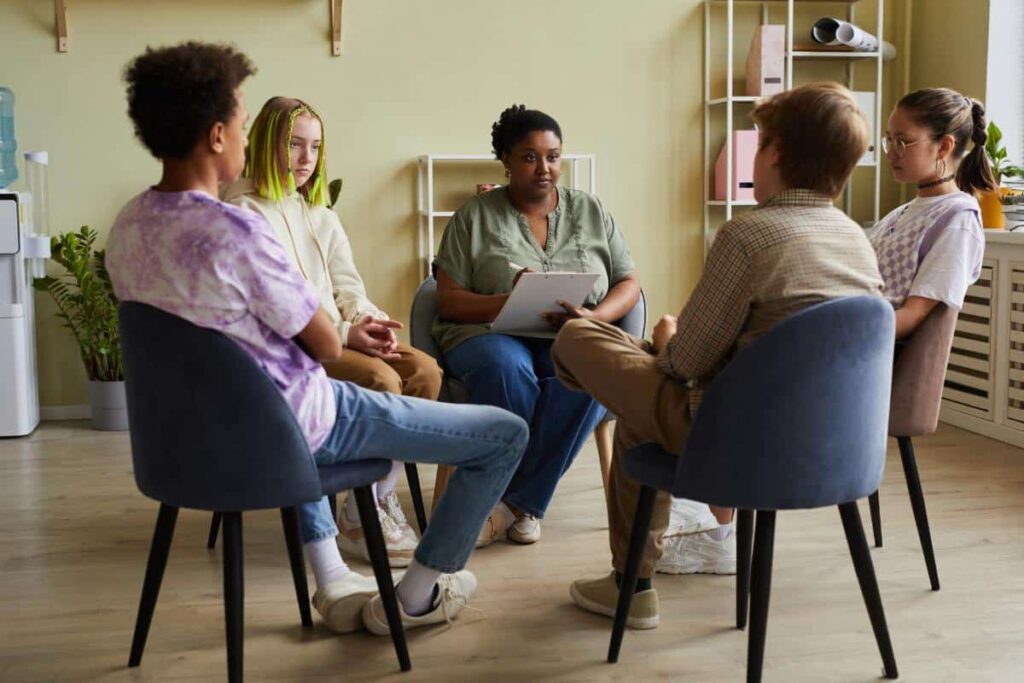 a group of teens discusses group therapy expectations with a therapist
