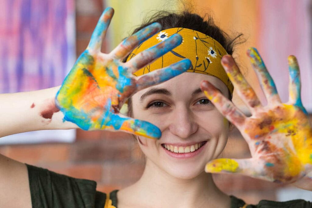 a teen hs paint on their hands smiling after asking what is art therapy?