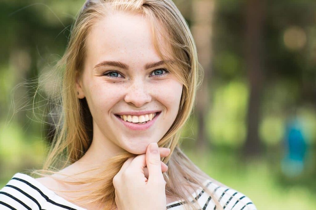 a teen girl smiles while outside while wondering to herself what is cognitive-behavioral therapy