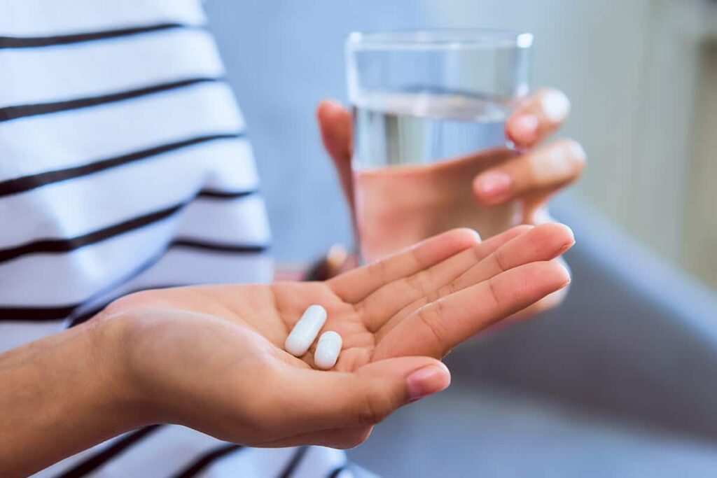 a hand holds two pills in a program for medication management in mental health