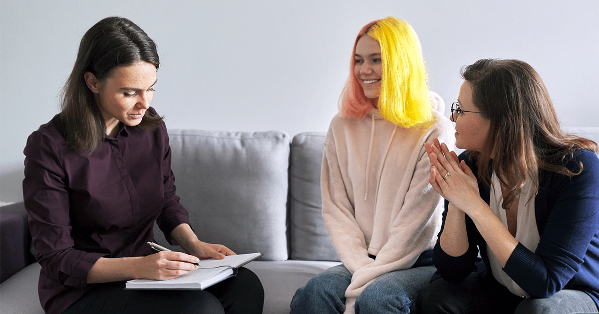 Teen smiling and talking to a counselor.